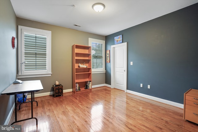 office area with visible vents, light wood-type flooring, and baseboards