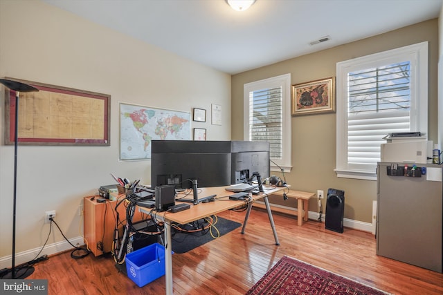 office area with visible vents, baseboards, and wood finished floors