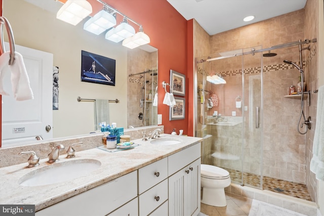 bathroom with a sink, toilet, double vanity, and a shower stall