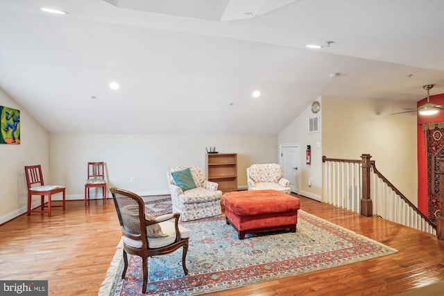 sitting room featuring an upstairs landing, light wood-type flooring, and vaulted ceiling