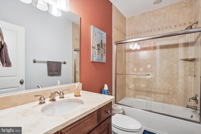 full bath with toilet, vanity, and shower / bath combination with glass door