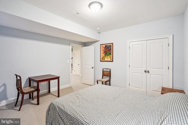 bedroom with a closet, light colored carpet, and baseboards