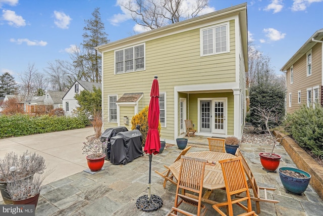 rear view of house featuring a patio area, french doors, and concrete driveway