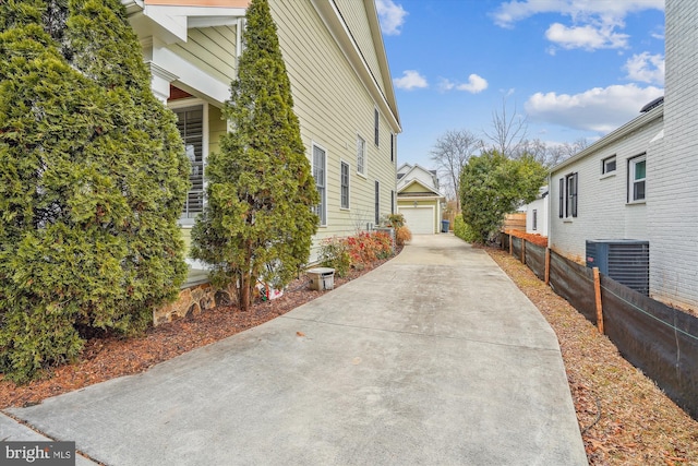 view of side of property featuring an outbuilding, cooling unit, fence, and a detached garage