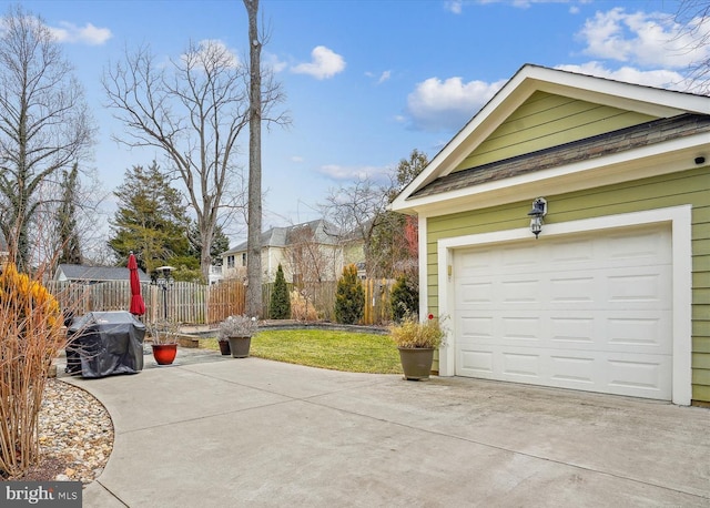 garage featuring concrete driveway and fence