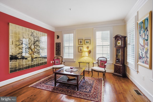 sitting room featuring visible vents, wood finished floors, baseboards, and ornamental molding