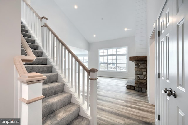 stairs featuring high vaulted ceiling and wood-type flooring