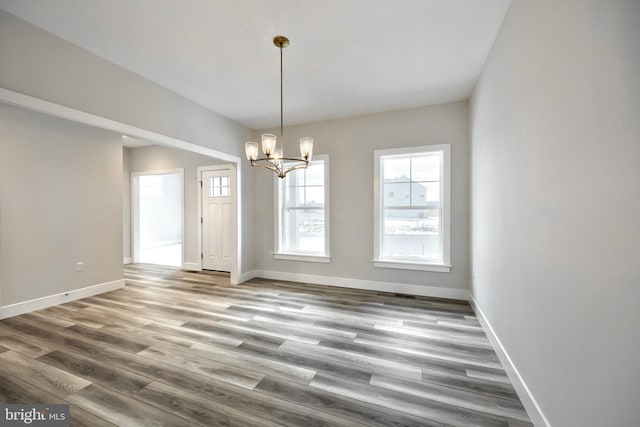 unfurnished dining area featuring hardwood / wood-style floors and a notable chandelier