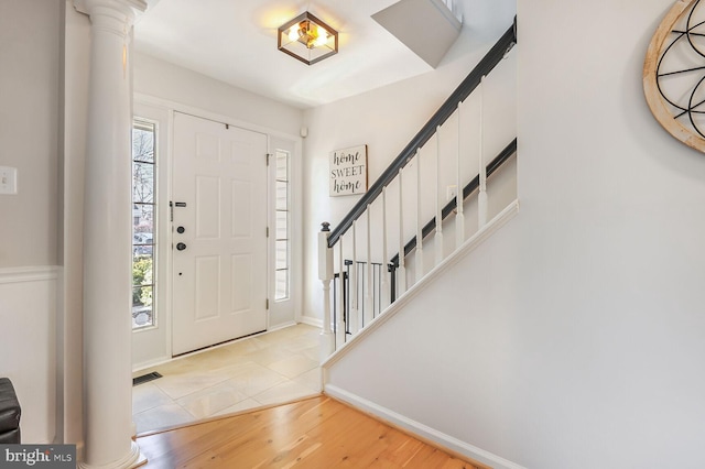 foyer entrance featuring decorative columns, light hardwood / wood-style floors, and a healthy amount of sunlight