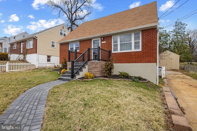 view of front of house with a front yard, brick siding, fence, and an outdoor structure