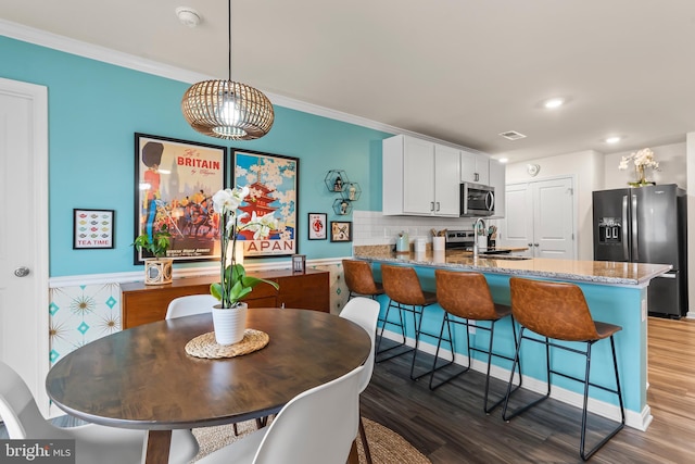 dining room with hardwood / wood-style floors, crown molding, and sink