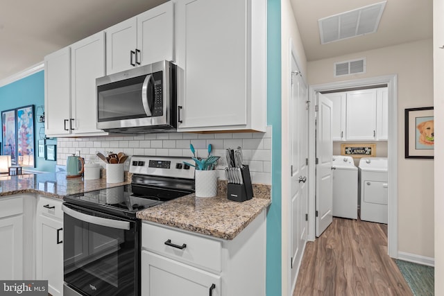 kitchen with white cabinetry, stainless steel appliances, tasteful backsplash, light stone counters, and washer and clothes dryer