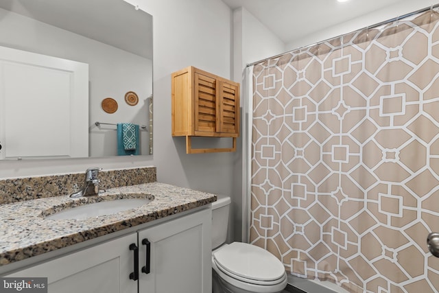 bathroom featuring toilet, vanity, and curtained shower