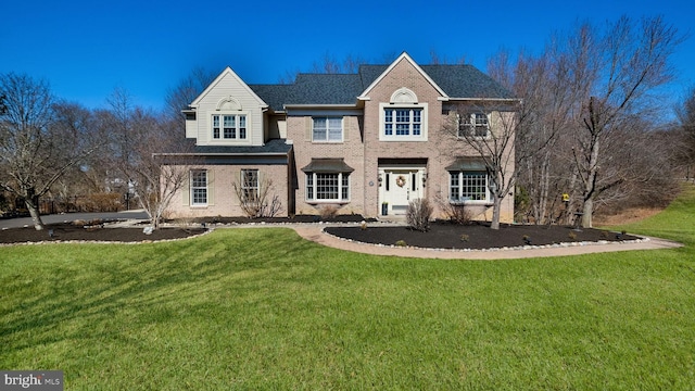 view of front facade featuring brick siding, a shingled roof, and a front yard