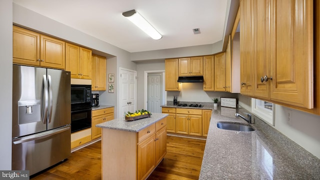 kitchen with visible vents, a kitchen island, under cabinet range hood, black appliances, and a sink