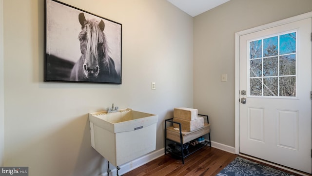 doorway featuring dark wood finished floors, baseboards, and a sink