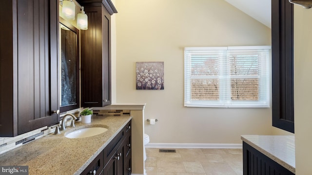 bathroom featuring visible vents, toilet, baseboards, vanity, and vaulted ceiling