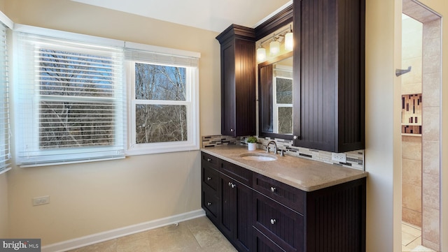 bathroom with vanity, tile patterned flooring, baseboards, and backsplash