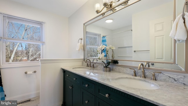 full bath with double vanity, a wealth of natural light, and a sink