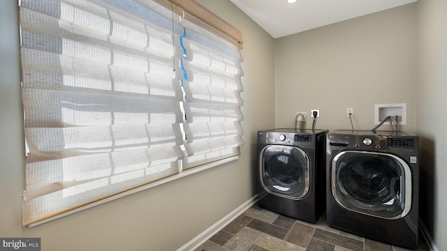 washroom with stone finish flooring, baseboards, laundry area, and washer and clothes dryer