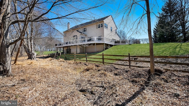 rear view of property featuring a yard, a wooden deck, a chimney, and fence