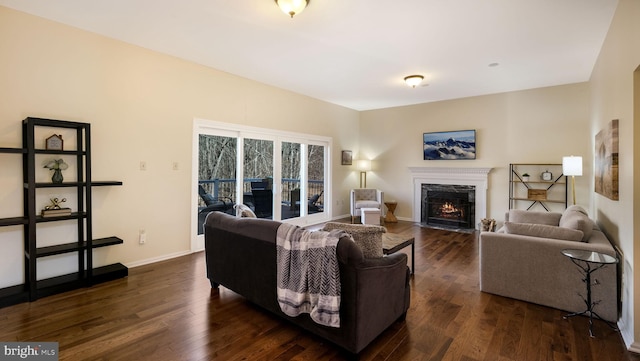 living room with baseboards, dark wood-style flooring, and a high end fireplace