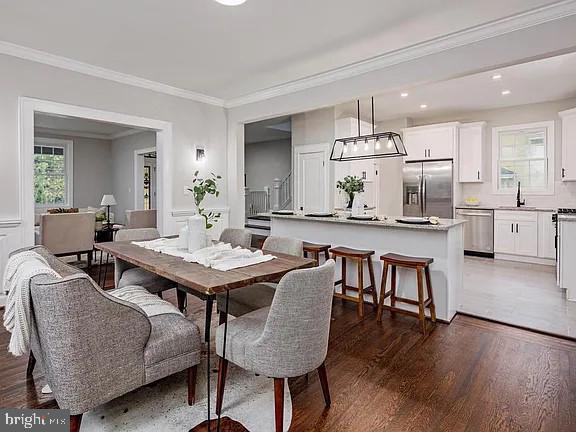 dining area with sink, dark hardwood / wood-style floors, and ornamental molding