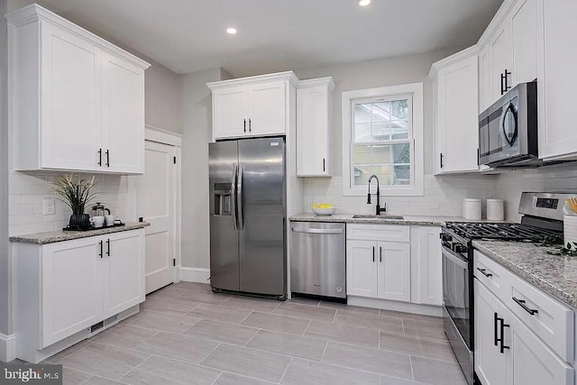 kitchen featuring sink, appliances with stainless steel finishes, white cabinetry, and light stone counters