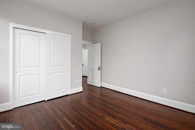 unfurnished bedroom with dark hardwood / wood-style flooring and a closet