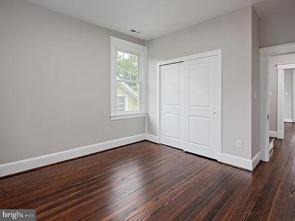 unfurnished bedroom with dark hardwood / wood-style flooring and a closet