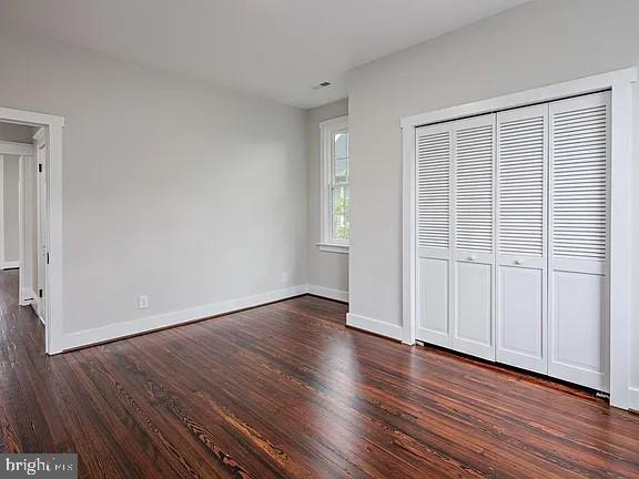 unfurnished bedroom with a closet and dark hardwood / wood-style floors