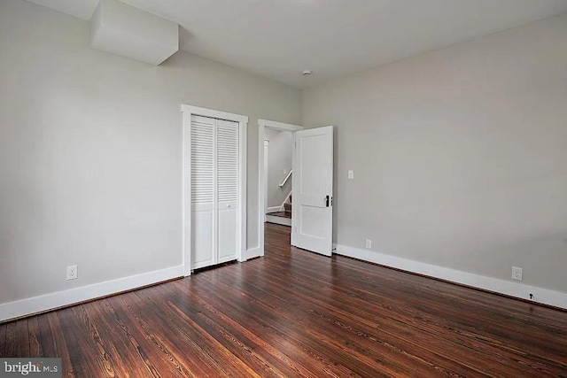 unfurnished bedroom with a closet and dark wood-type flooring