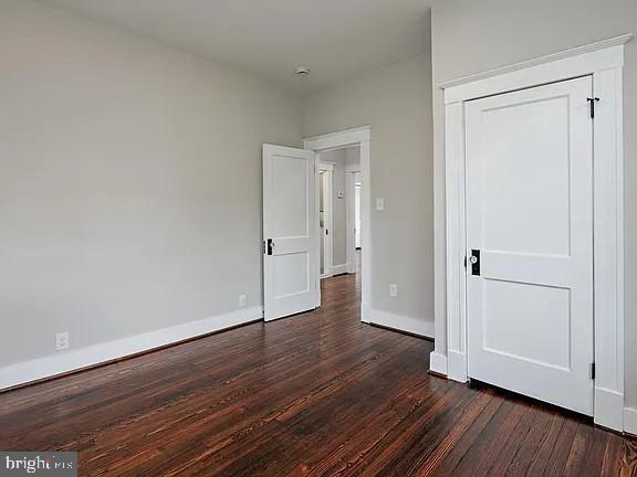 unfurnished bedroom with dark hardwood / wood-style floors and a closet