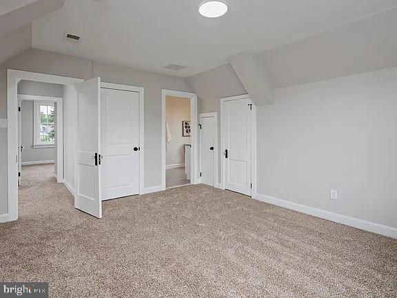 bonus room with vaulted ceiling and carpet flooring