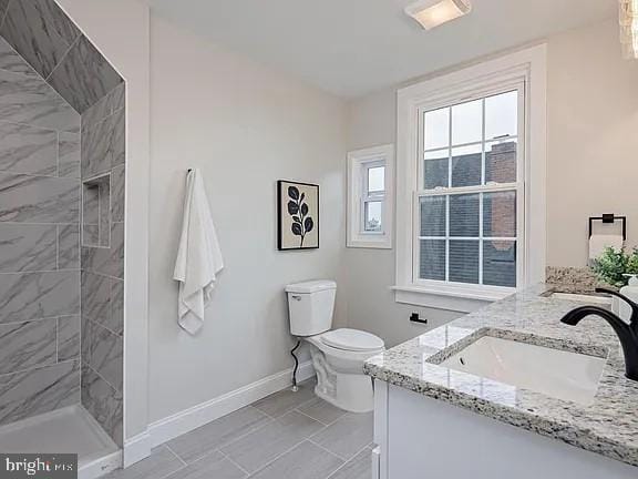 bathroom with vanity, a tile shower, and toilet