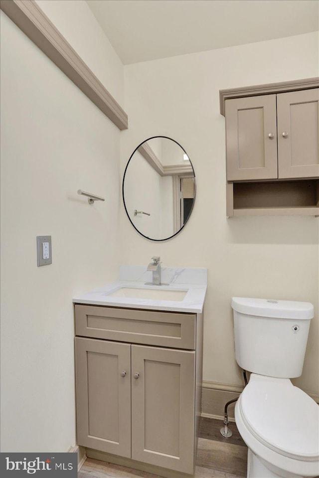 bathroom featuring baseboards, vanity, toilet, and wood finished floors