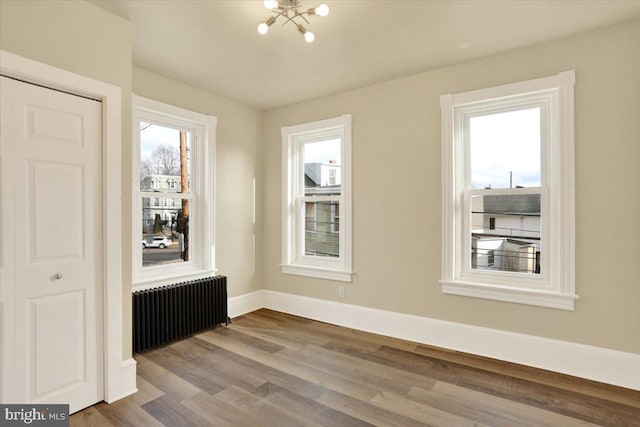 interior space with an inviting chandelier, radiator, baseboards, and wood finished floors