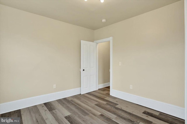 spare room with baseboards and wood finished floors