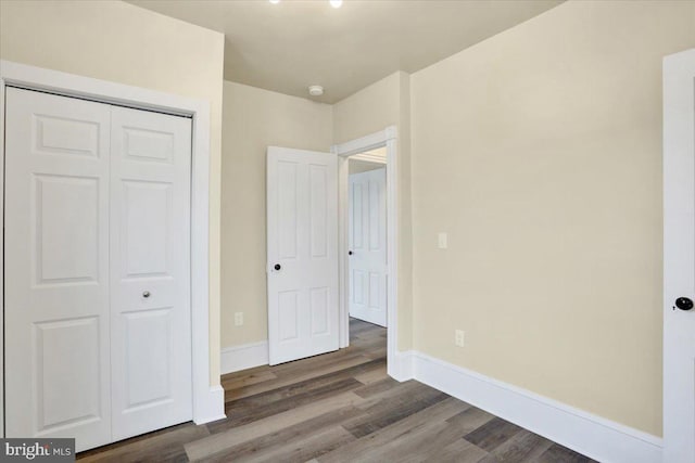 unfurnished bedroom featuring a closet, wood finished floors, and baseboards