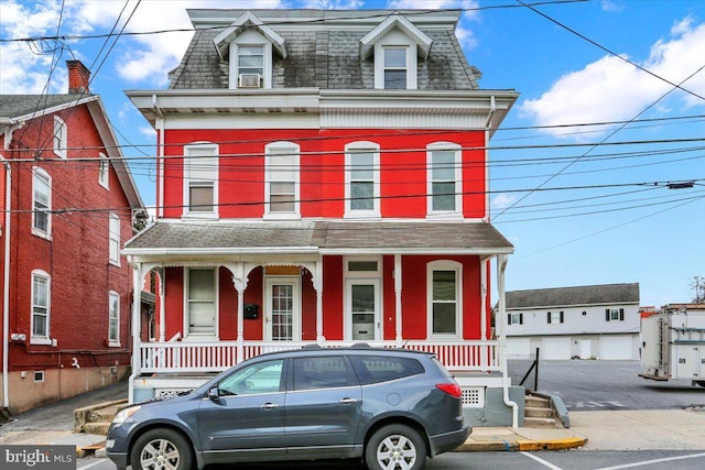 second empire-style home featuring a porch and mansard roof