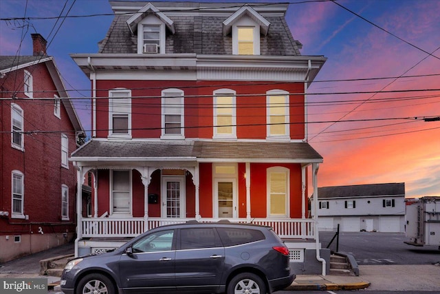 victorian home featuring a shingled roof, covered porch, and mansard roof