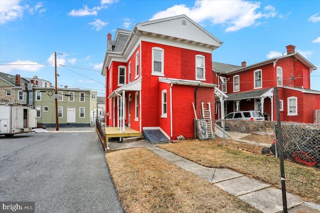 view of front facade with a residential view, fence, and brick siding