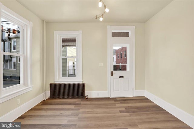 interior space featuring radiator heating unit, baseboards, and light wood-style flooring