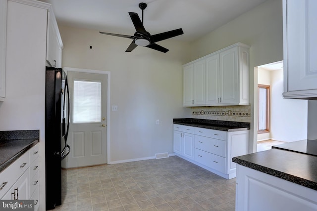 kitchen with dark countertops, decorative backsplash, white cabinets, and freestanding refrigerator