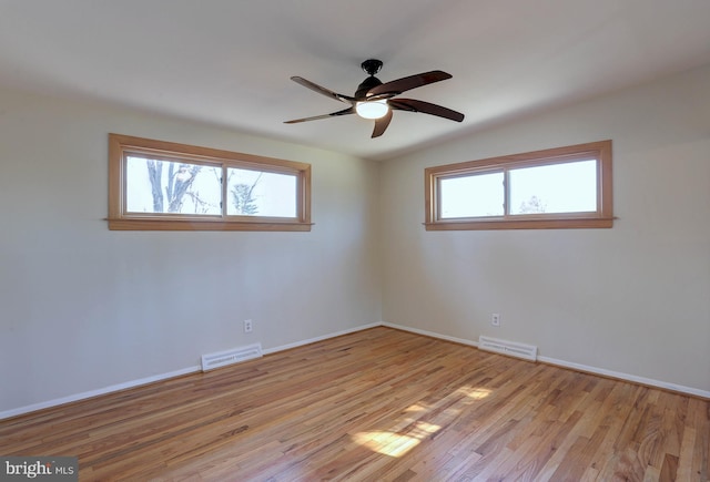 spare room featuring a wealth of natural light, visible vents, and light wood-style floors