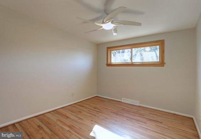 spare room featuring ceiling fan, light wood-style floors, visible vents, and baseboards