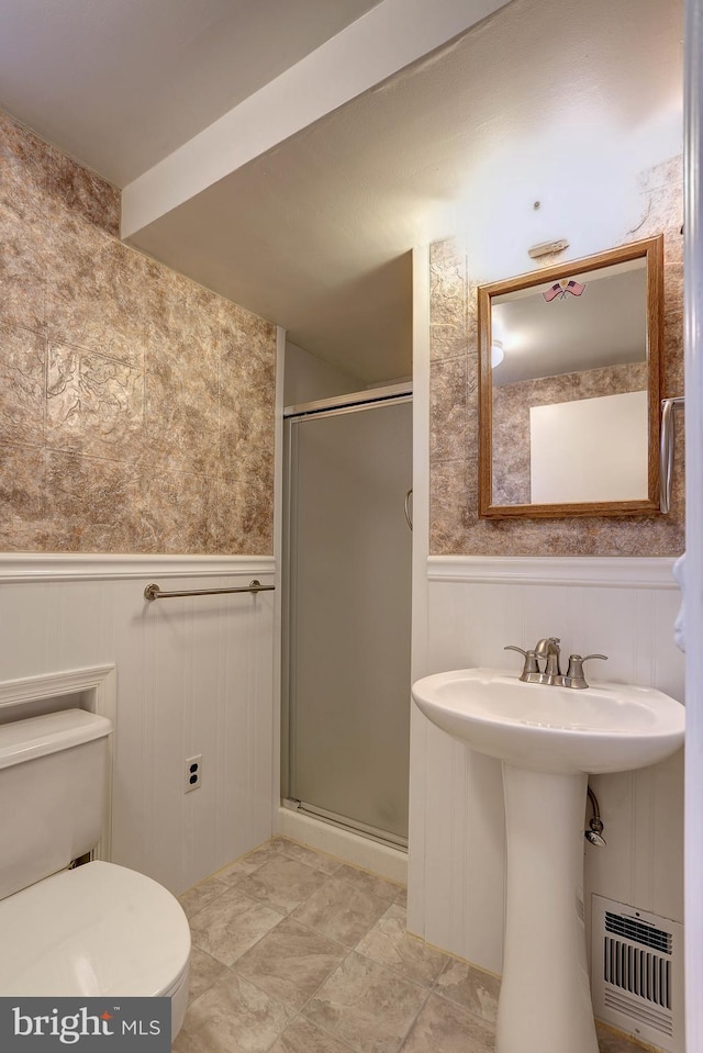 bathroom with a wainscoted wall, a shower stall, and visible vents