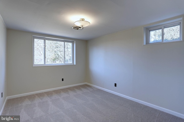 spare room featuring plenty of natural light, baseboards, and light carpet