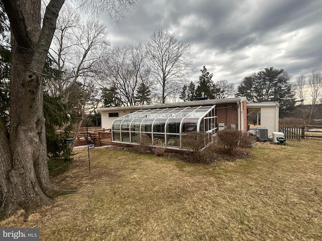 back of property featuring a yard, fence, brick siding, and a sunroom