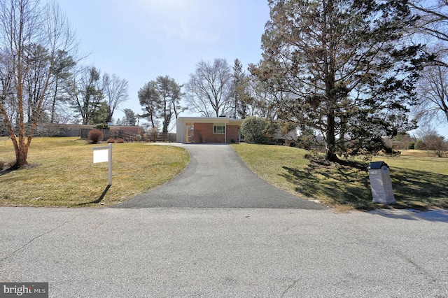 ranch-style home with brick siding, driveway, a front yard, and fence